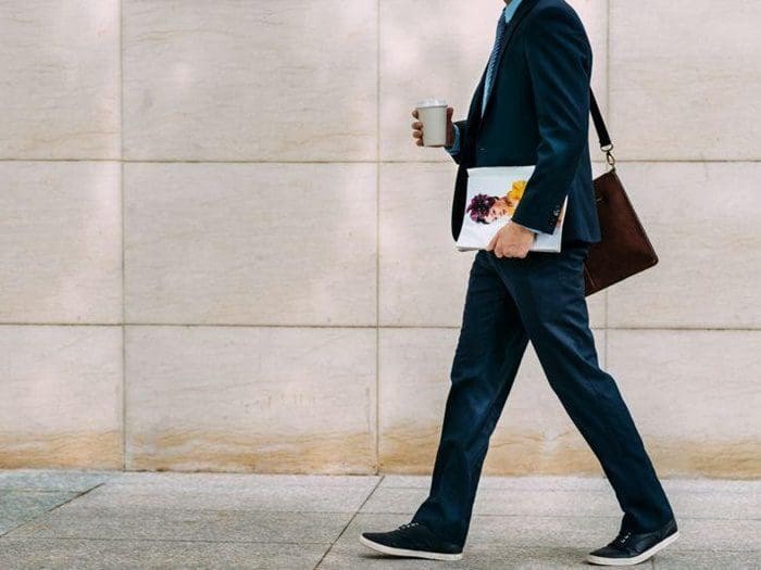 homem segurando uma revista e um copo de café indo trabalhar simbolizando escala 5x2
