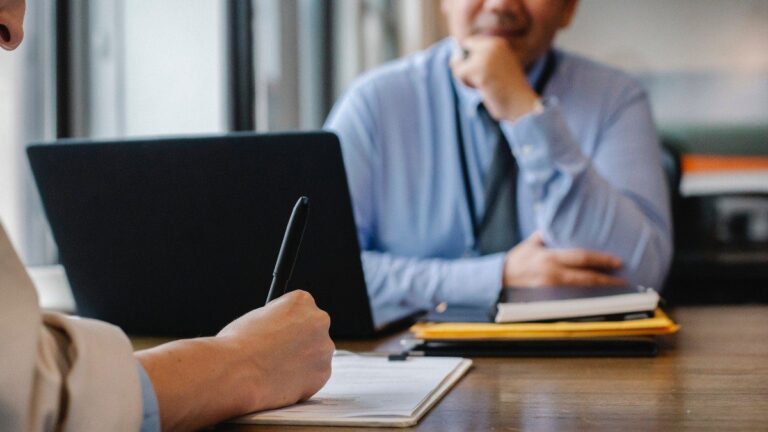 Imagem de um colaborador e um gestor conversando em uma mesa de escritório. Usamos a imagem para ilustrar o post sobre demissão por justa causa