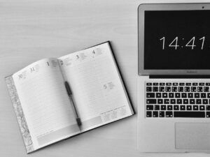 Imagem de uma agenda e um notebook sob uma mesa