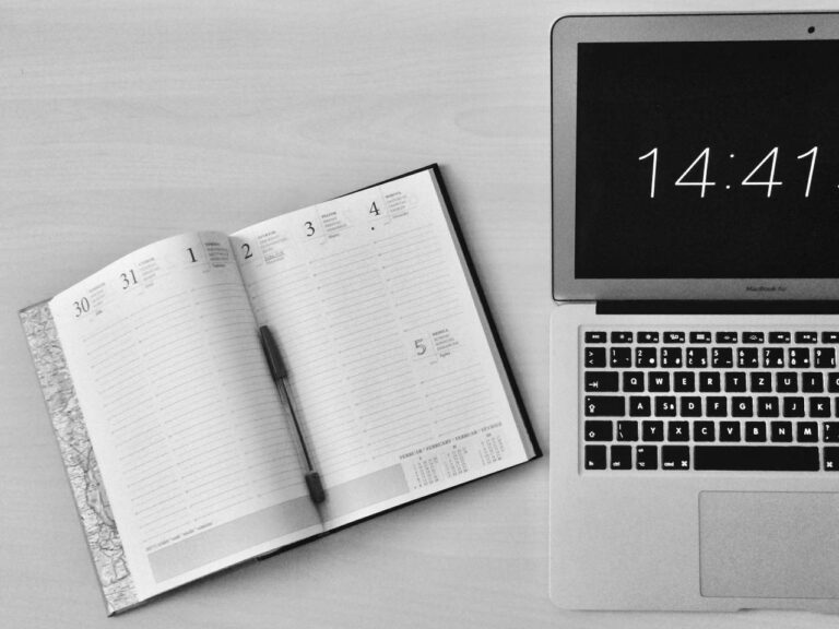 Imagem de uma agenda e um notebook sob uma mesa