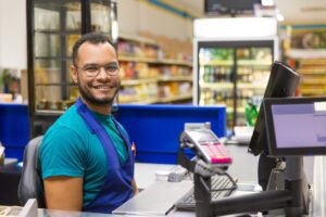 Homem trabalhando como atendente de caixa de supermercado