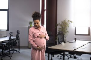 Mulher negra grávida segurando a barriga