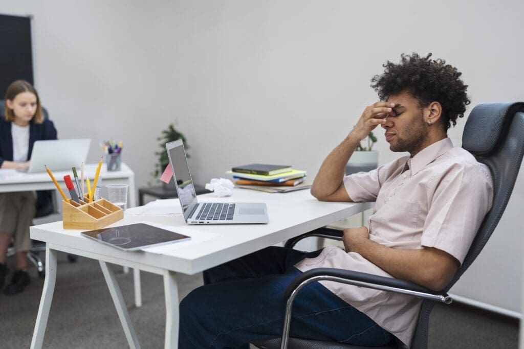 Homem sentado em mesa com a mão na cabeça