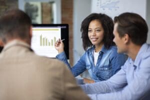 Mulher negra apresentando gráficos para equipe de trabalho