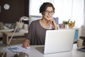 Mulher branca de cabelo escuro olhando para tela de computador