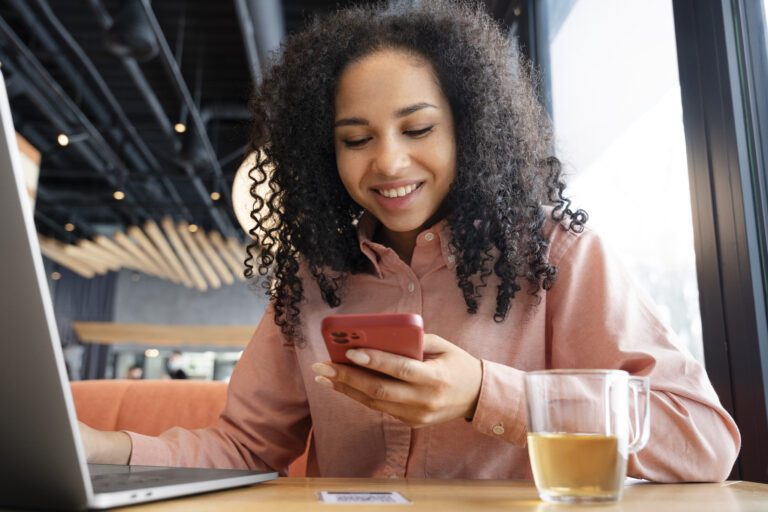 Mulher negra olhando para celular.